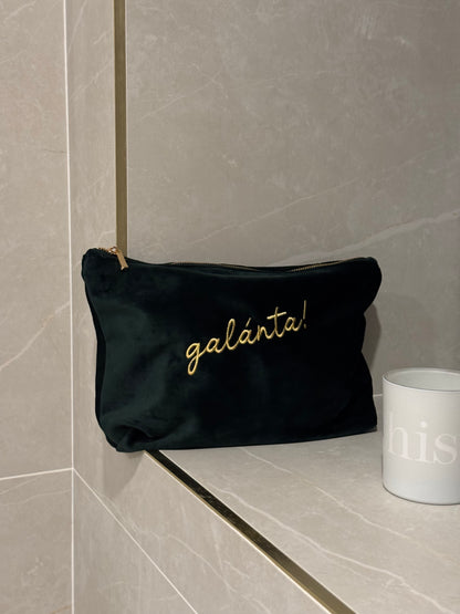 Emerald pouch with 'galánta' embroidery on a tiled bathroom shelf.