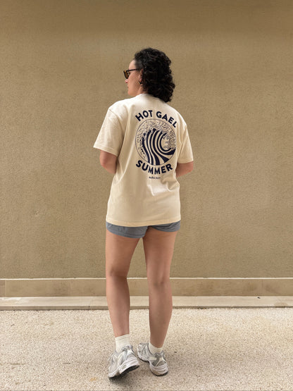 Person wearing a cream t-shirt with Hot Gael Summer text and graphics, standing against a beige wall.