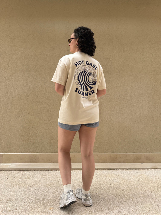 Person wearing a cream t-shirt with Hot Gael Summer text and graphics, standing against a beige wall.