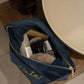 Open navy blue makeup bag with cosmetic items on a wooden surface