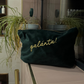 Dark green pouch with 'galanta!' text on a counter in a bathroom setting